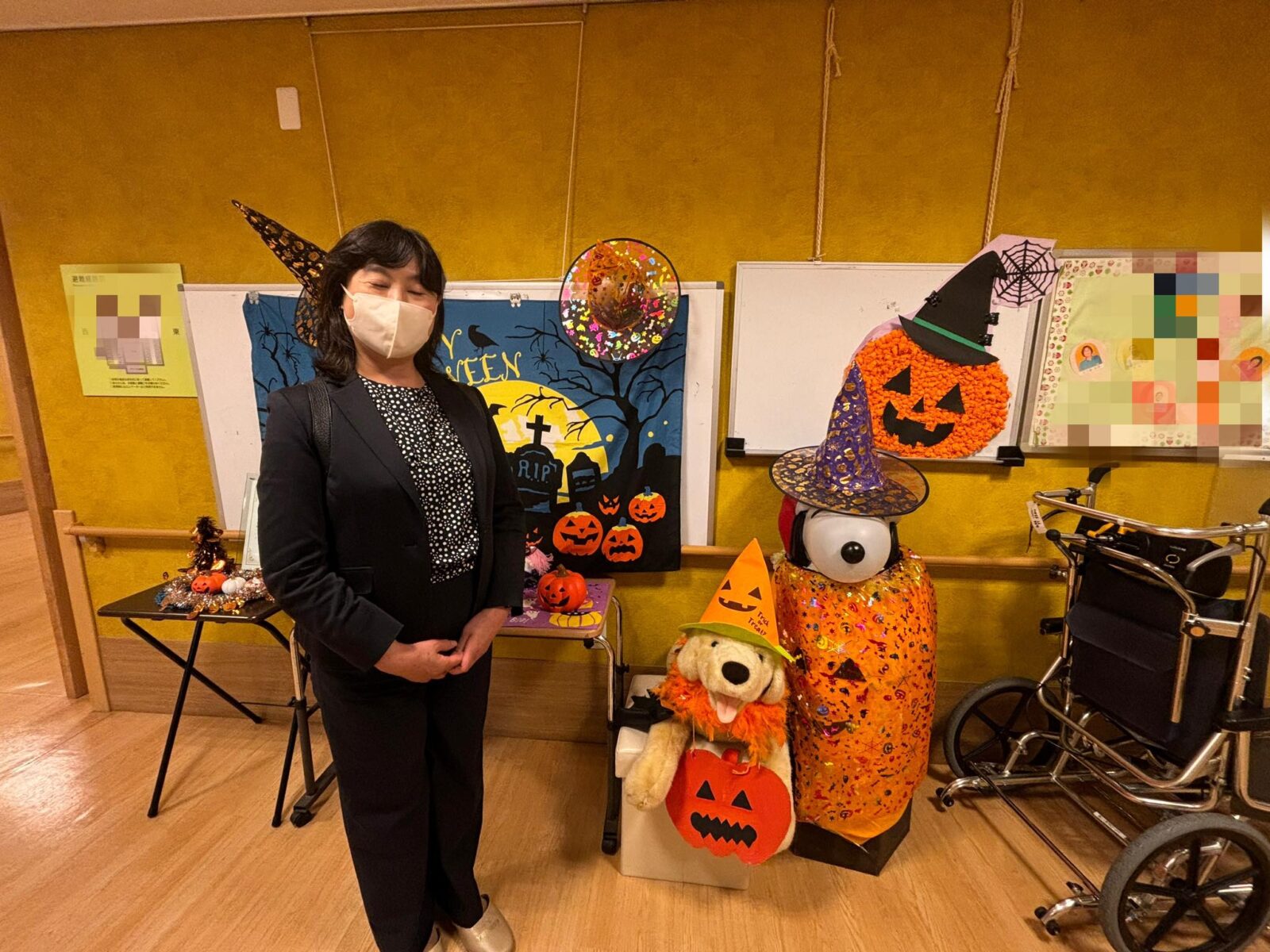 ハロウィーンの飾り付けがされた施設で、笑顔を見せる入江あき子県議。装飾にはかぼちゃや帽子が並ぶ。
